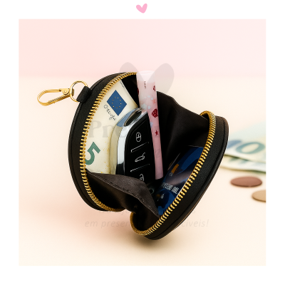 Estojo redondo preto com fecho dourado aberto com objetos pessoais dentro.