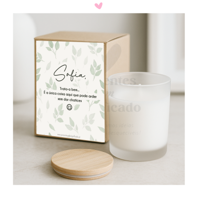 Vela branca em copo de vidro fosco com tampa de madeira e caixa com etiqueta decorativa e texto em português