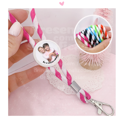 Cordão para porta-chaves personalizável em tecido branco e rosa com botão redondo com foto e texto, fecho e mosquetão, em fundo rosa claro.