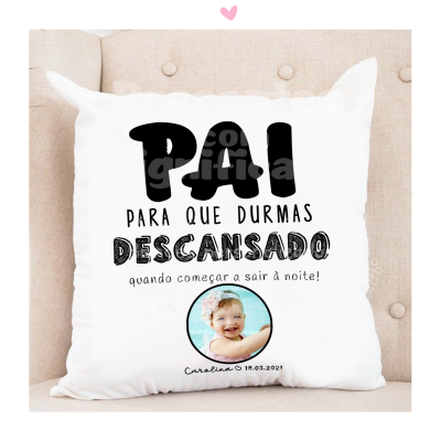 Almofada branca com texto em preto e foto de bebé, sobre cadeira bege
