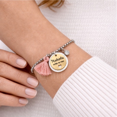 Pulseira prata com pendente dourado e text na pele do pulso