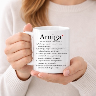 Caneca branca com texto Amiga e definições em português, sendo segurada por mãos femininas.