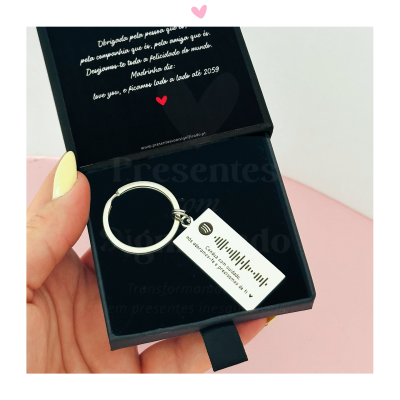 Chaveiro metálico prateado em estojo preto com etiqueta branca e código de barras