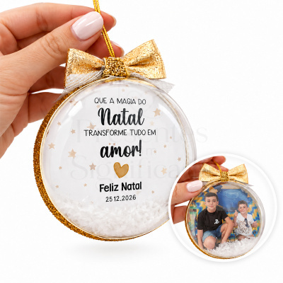 Bola de Natal transparente com laço dourado e texto em português, com fotografia de duas crianças no interior.