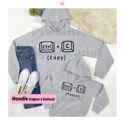 Hoodies cinzentos com estampas Ctrl C Copy e Ctrl V Paste, ao lado de ténis brancos e jeans azuis sobre fundo claro.