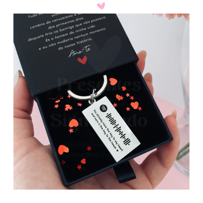 Chaveiro retangular prata com código Spotify numa caixa preta decorada com corações vermelhos