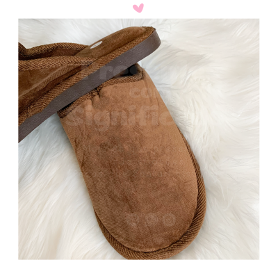 Chinelos castanhos tipo camurça sobre superfície branca felpuda