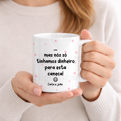 Caneca branca com pontos rosa e texto a negro segurada por mãos femininas