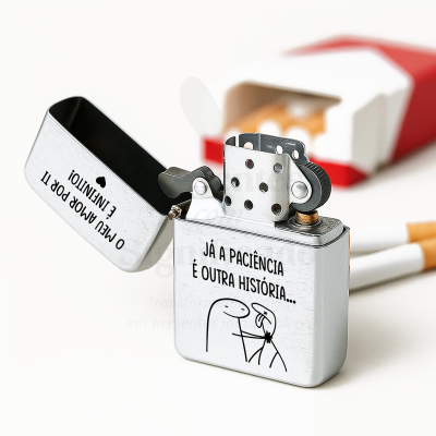 Isqueiro prateado com texto em português e desenho minimalista, com um pack de cigarros ao fundo.