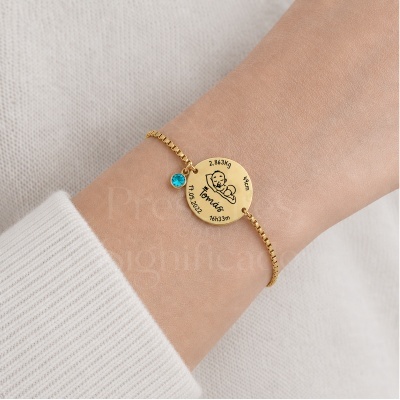 Pulseira dourada com pendente redondo personalizado e pendente azul no pulso.