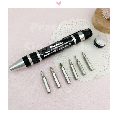 Conjunto de mini-chaves de fendas com cabo preto e prata e texto personalizado, sobre tecido rosa e renda branca