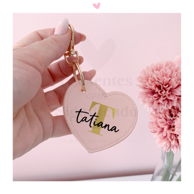 Chaveiro coração cor-de-rosa com nome Tatiana, segurado por mão junto a flores cor-de-rosa