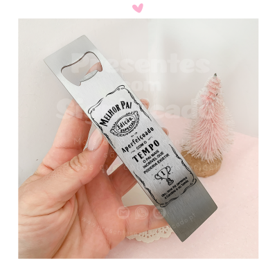 Abridor de garrafas metálico com gravação para pai, em fundo branco com árvore decorativa rosa.