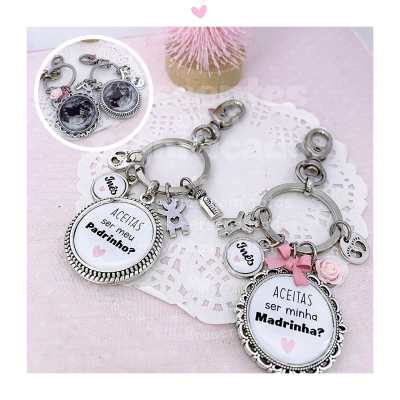 Porta-chaves prateados com mensagens para padrinho e madrinha, decorados com pendentes em fundo rosa e renda branca