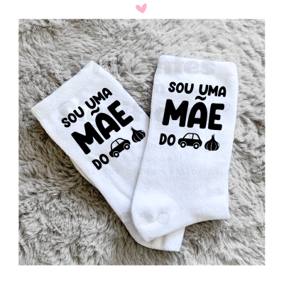 Meias brancas com texto preto e ícones de carro e alho sobre tecido cinzento