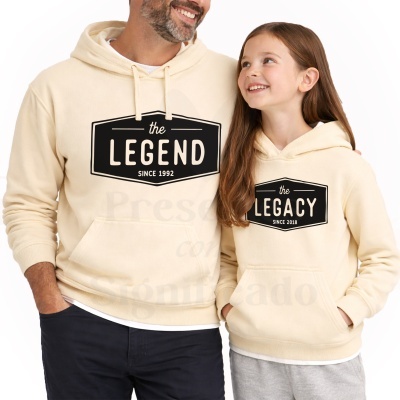 Pai e filha com sweatshirts bege com capuz e bolsos canguru, texto preto the LEGEND e the LEGACY.