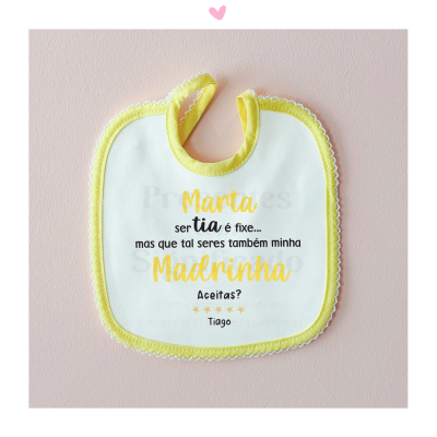 Babete branco com bordos amarelos e texto para madrinha, fundo rosa com coração