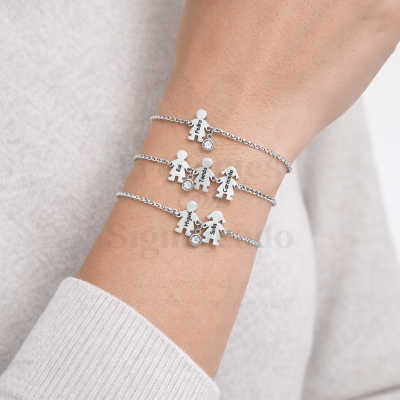 Pulseiras prateadas com figuras de família e pedras brilhantes num braço com camisola cinza