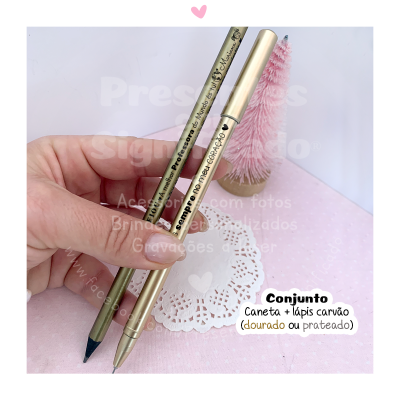 Conjunto de caneta dourada e lápis carvão em fundo rosa com pinheiro e papel rendado branco