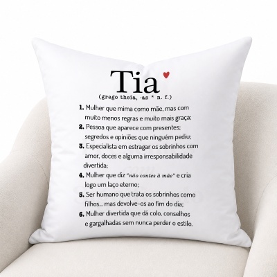Almofada branca com texto em português definindo Tia, com um pequeno coração vermelho, sobre sofá claro.