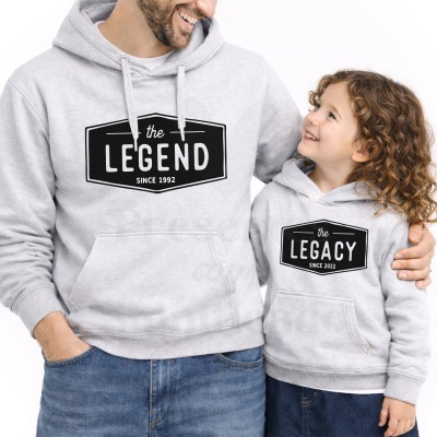 Pai e filha com sweatshirts cinzentas com capuz com texto preto.