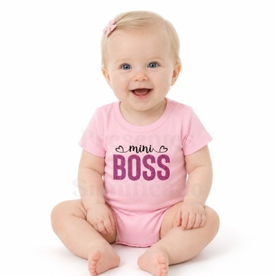 Bebé com body rosa e texto mini BOSS sentado