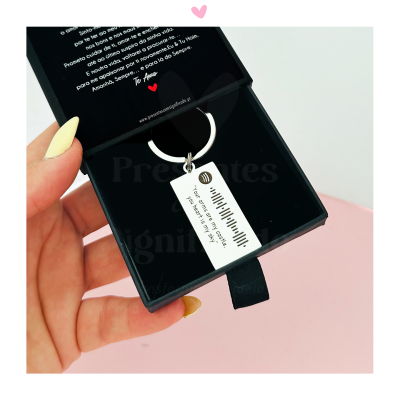 Chaveiro prateado com pendente branco e código de barras de som em caixa preta