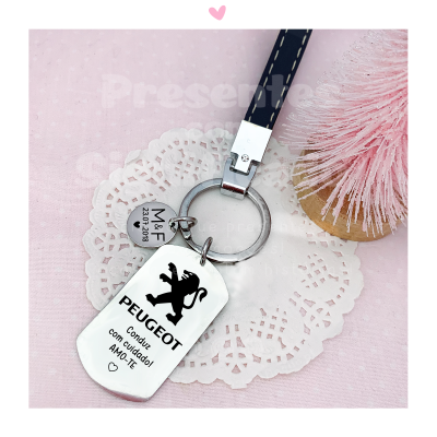 Porta-chaves Peugeot metálico com correia preta e gravura em fundo rosa.