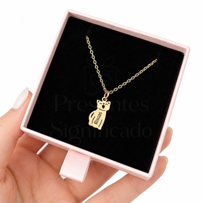 Colar dourado com pendente de gato numa caixa rosa clara com interior negro