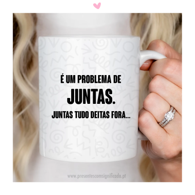 Caneca branca com texto humorístico em preto sobre problema de juntas, segurada por mão com anéis.