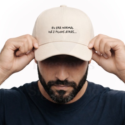 Boné bege claro com texto preto e homem com barba a segurá-lo.