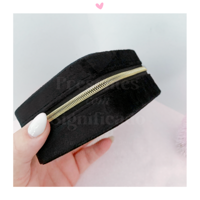 Bracelete preta de tecido com fecho metálico dourado segurada por mão