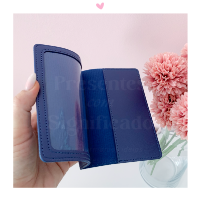 Carteira ou porta-cartões azul escuro com compartimento transparente e flores cor de rosa ao fundo
