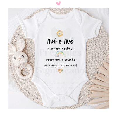 Body branco para bebé com texto e imagens coloridas sobre tapete redondo de palha, rodeado por brinquedo de coelho e adorno decorativo de madeira