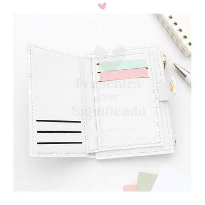 Carteira branca aberta com cartões coloridos pastel, caderno espiral e caneta prateada ao fundo