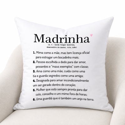 Almofada branca com texto sobre significado da palavra Madrinha, com detalhe de coração rosa, sobre cadeira bege.