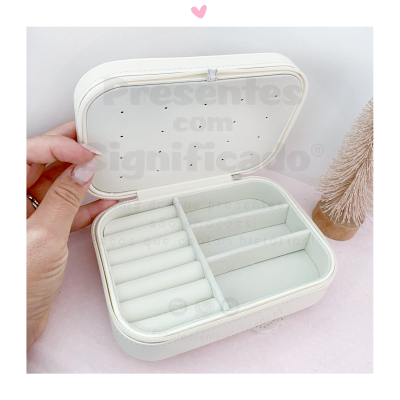 Estojo de joias branco aberto com divisórias para anéis e outras joias, mão a segurar a tampa