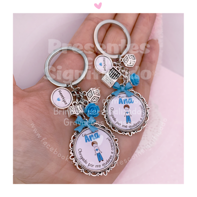 Chaveiros personalizados com fotos e enfeites em metal e resina azul na mão.