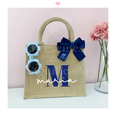 Saco de mão bege com alça, laço azul e óculos de sol azuis em forma de flores