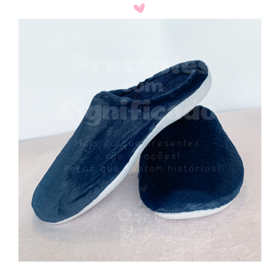 Pantufas pretas felpudas com sola branca sobre superfície clara