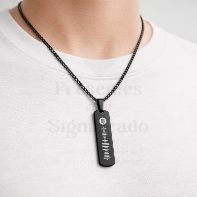 Colar preto com pingente retangular e desenho gráfico branco sobre t-shirt branca.