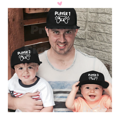 Três pessoas com bonés pretos 'PLAYER 1', 'PLAYER 2' e 'PLAYER 3' sentados junto a parede de tijolos e porta de madeira