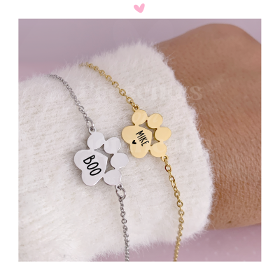 Pulseiras dourada e prateada com pendentes florais com as palavras BOO e MILK, usadas num pulso com manga branca felpuda