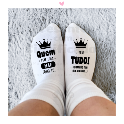 Meias brancas com texto preto e coroas pretas sobre fundo cinza felpudo.