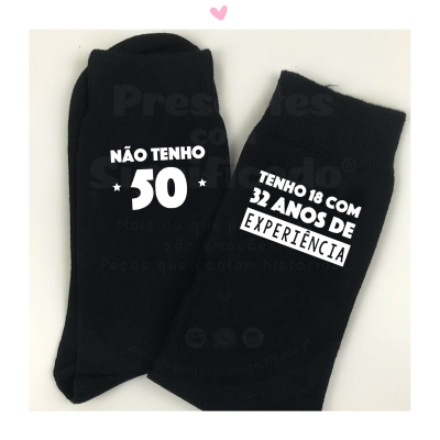 Par de meias pretas com textos brancos sobre fundo branco e coração rosa.