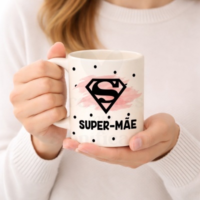 Caneca branca com pontos pretos e texto SUPER-MÃE segurada por pessoa com suéter branco