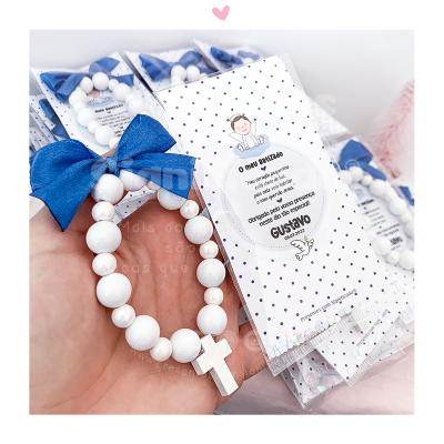 Terço infantil branco com laço azul e cartão decorativo com texto sobre batizado de Gustavo