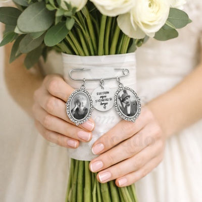 Agulha com medalhões e fotos pendurados num ramo de flores brancas.