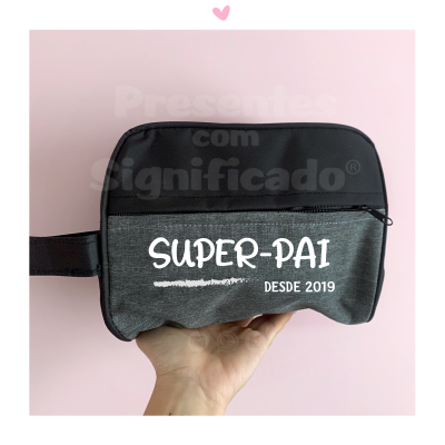 Necessaire cinza e preta com texto SUPER-PAI e DESDE 2019, fundo rosa claro com coração