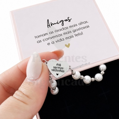 Pulseira de contas brancas e pendente metálico com texto, dentro de caixa de oferta rosa com mensagem sobre amizade